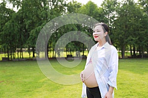 Asian Eastern Chinese happy pregnant woman hands on belly expecting baby to born be a good mother enjoy nature outdoor time