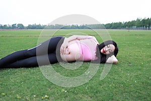 Asian Eastern Chinese happy pregnant woman lying on grass meadow in outdoor nature close eyes have a rest enjoy carefree time