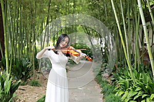 Asian Eastern Chinese young artist player woman carry play violin perform music park garden nature outdoor bamboo path