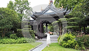 Asian Eastern Chinese young artist player woman carry play violin perform music park garden outdoor nature ancient building