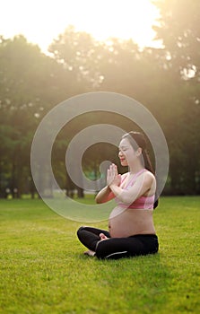 Asian Eastern Chinese young pretty pregnant girl woman do yoga sit in meditation, do lotus gesture of yoga over sunset,namaste