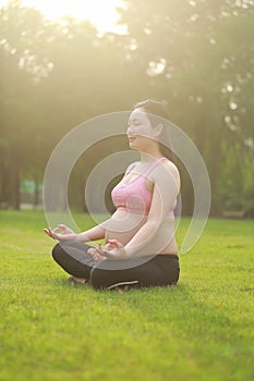 Asian Eastern Chinese young pretty pregnant girl woman do yoga sit in meditation, do lotus gesture of yoga over sunset,namaste