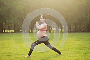 Asian Eastern Chinese young pretty pregnant girl woman do yoga stand in meditation, do lotus gesture of yoga outdoor nature sunset