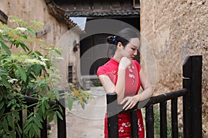 Asian Eastern oriental Chinese woman beauty in traditional ancient dress costume red cheongsam in ancient town garden fence