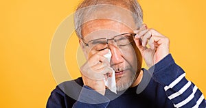 Asian elder man crying raise glasses with tissue wipe red eyes