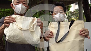 Asian elder senior couple wearing mask encourage using cotton bag recycleable for grocery shopping