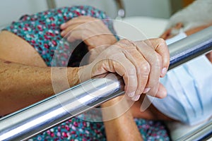 Asian elder senior woman patient holding bed rail while lie down with hope waiting her family in hospital