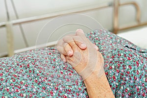 Asian elder senior woman patient holding bed rail while lie down with hope waiting her family in hospital