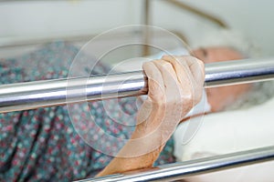 Asian elder senior woman patient holding bed rail while lie down with hope waiting her family in hospital