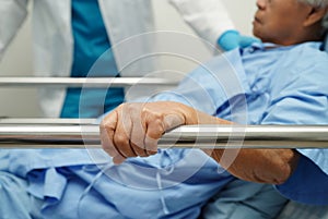 Asian elder senior woman patient holding bed rail while lie down with hope waiting her family in hospital