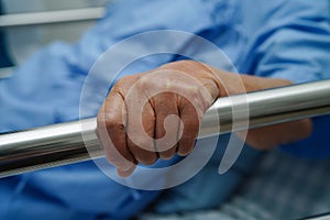 Asian elder senior woman patient holding bed rail while lie down with hope waiting her family in hospital