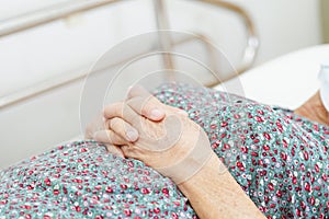 Asian elder senior woman patient holding bed rail while lie down with hope waiting her family in hospital