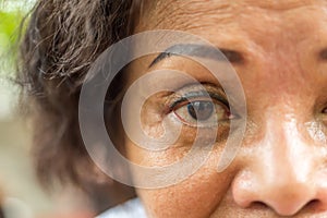 Asian elder women show her eyes and eyebrow tattoo
