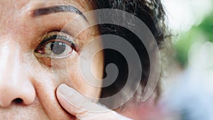 Asian elder women show her eyes and eyebrow tattoo