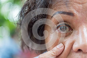 Asian elder women show her eyes and eyebrow tattoo