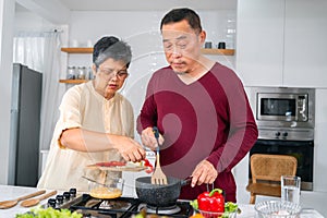 Asian elderly couple cooking in kitchen to prepare dinner