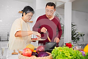 Asian elderly couple cooking in kitchen to prepare dinner