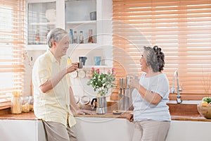 Asian elderly couple drinking warm coffee and talking together in kitchen at home. Chinese couple enjoy love moment while taking