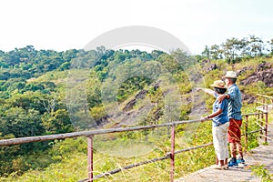 Asian elderly couple enjoying traveling Standing on the mountain looking at the beautiful natural scenery.