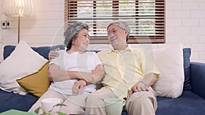 Asian elderly couple feeling happy smiling and looking to camera while relax on the sofa in living room at home.