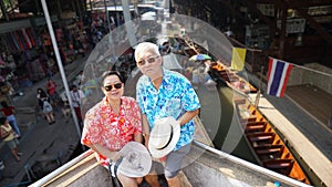 Asian elderly couple having retirment trip to Thailand floating