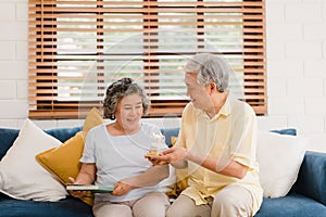 Asian elderly couple man holding cake celebrating wife`s birthday in living room at home. Japanese couple enjoy love moment