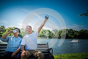 Asian elderly couple sitting, holding glass and drinking milk