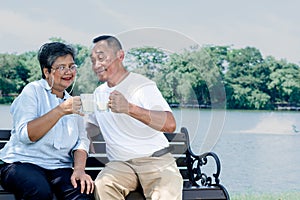 Asian elderly couple sitting and holding a glass of milk, they smile and happy