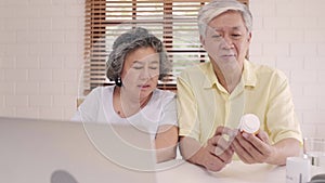 Asian elderly couple using laptop conference with doctor about medicine information in living room, couple using time together