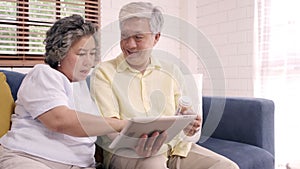 Asian elderly couple using tablet search medicine information in living room, couple using time together.