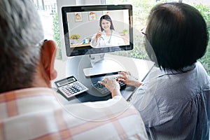 Asian elderly couples using computers Online video calling Talk to the doctor from home to inquire about health problems. photo