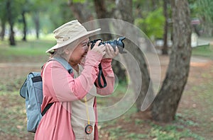 Asian elderly female tourist takes photo with camera. Professional photography. photo