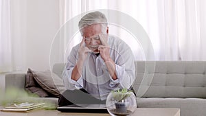 Asian Elderly have a headache. On the sofa in the living room