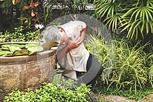 Asian elderly man acute heartache His head leaned against the edge of the lotus basin.