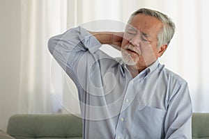 Asian Elderly man with a headache sitting on a bed in morning