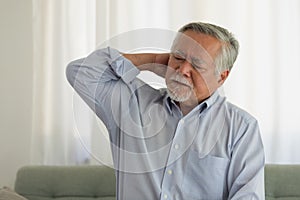 Asian Elderly man with a headache sitting on a bed in morning