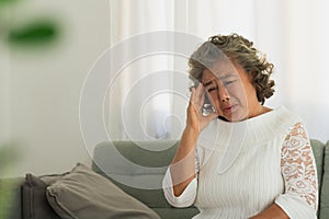 Asian Elderly man with a headache sitting on a bed in morning