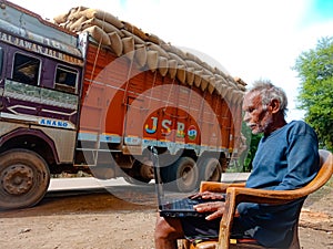 asian elderly man learning about laptop computer system at road side in india January 2020