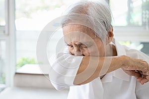 Asian elderly people sneezing,coughing into her sleeve or elbow to prevent spread Covid-19,Corona virus,sick senior woman has flu,