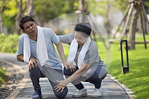 Asian elderly or senior man accident falling down on floor in the park while running exercise have pain knee ache