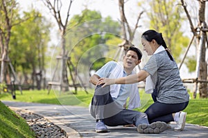 Asian elderly or senior man accident falling down on floor in the park while running exercise have pain knee ache