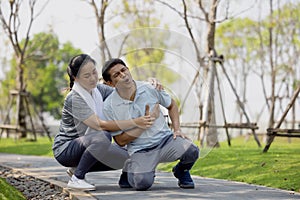 Asian elderly or senior man accident falling down on floor in the park while running exercise have pain knee ache