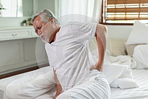 Asian Elderly senior man back pain and illness on bed at home,unhappy elderly touch on back serious and tried,Elderly Care Concept