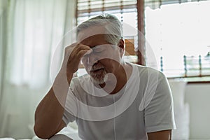 Asian Elderly senior man white hairs headache and migraine so pain,Stress senior man sit on bed at home alone,unhappy elderly
