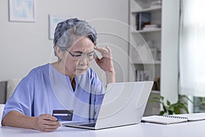 Asian elderly senior retired woman, stressed worried sad frustrated female having problem with paying, buying online