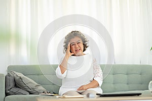 Asian Elderly senior woman sudden headache and migraine so pain and illness on sofa alone at home,Pensioner stress and headache