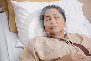 Asian elderly woman asleep on bed with surveillance in hospital ward, patient senior unconscious lying on bed.