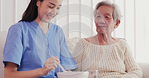 Asian elderly woman being fed by a nurse by volunteer with happy emotion.