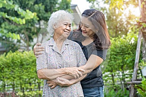 Asian elderly woman with caregiver daughter walking and hug with happy in nature park