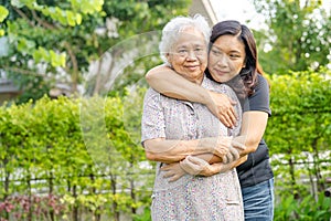 Asian elderly woman with caregiver daugther walking and hug with happy in nature park